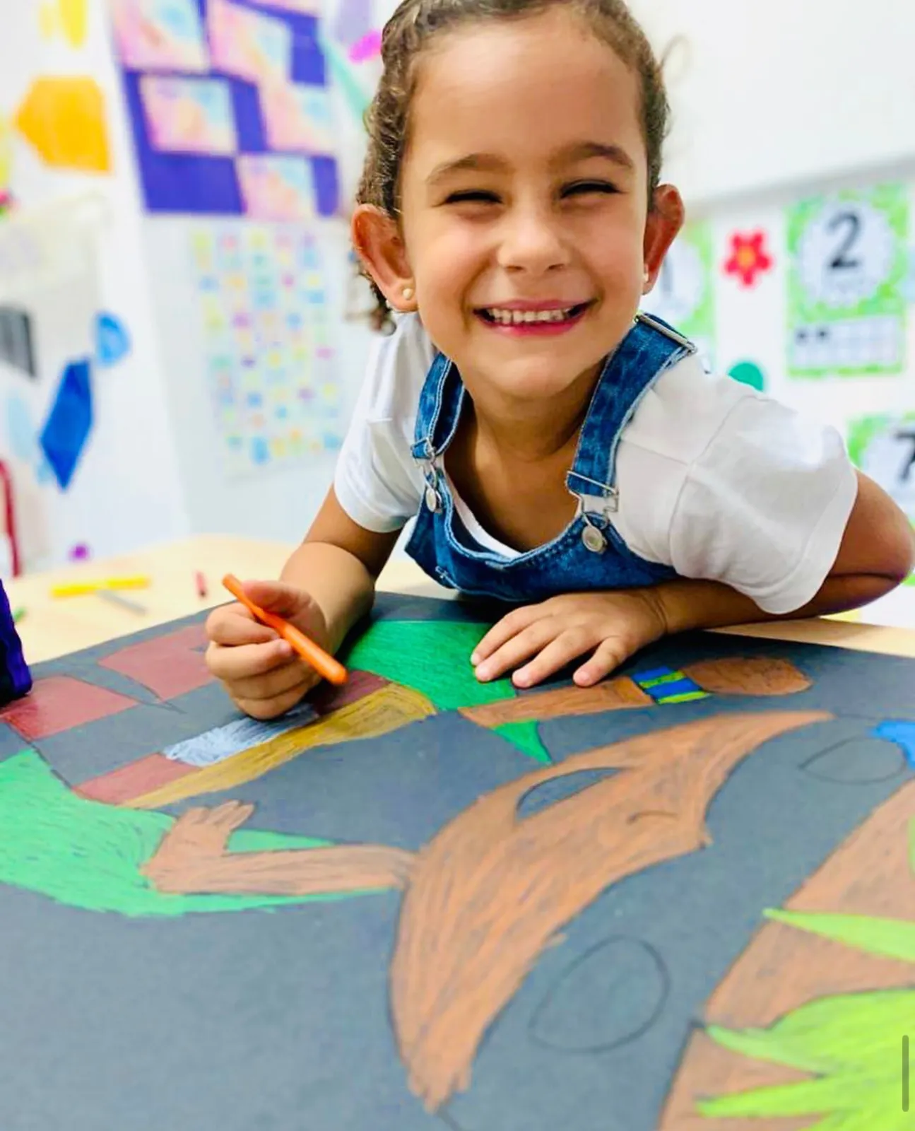 Niña sonriente pintando un dibujo en clase